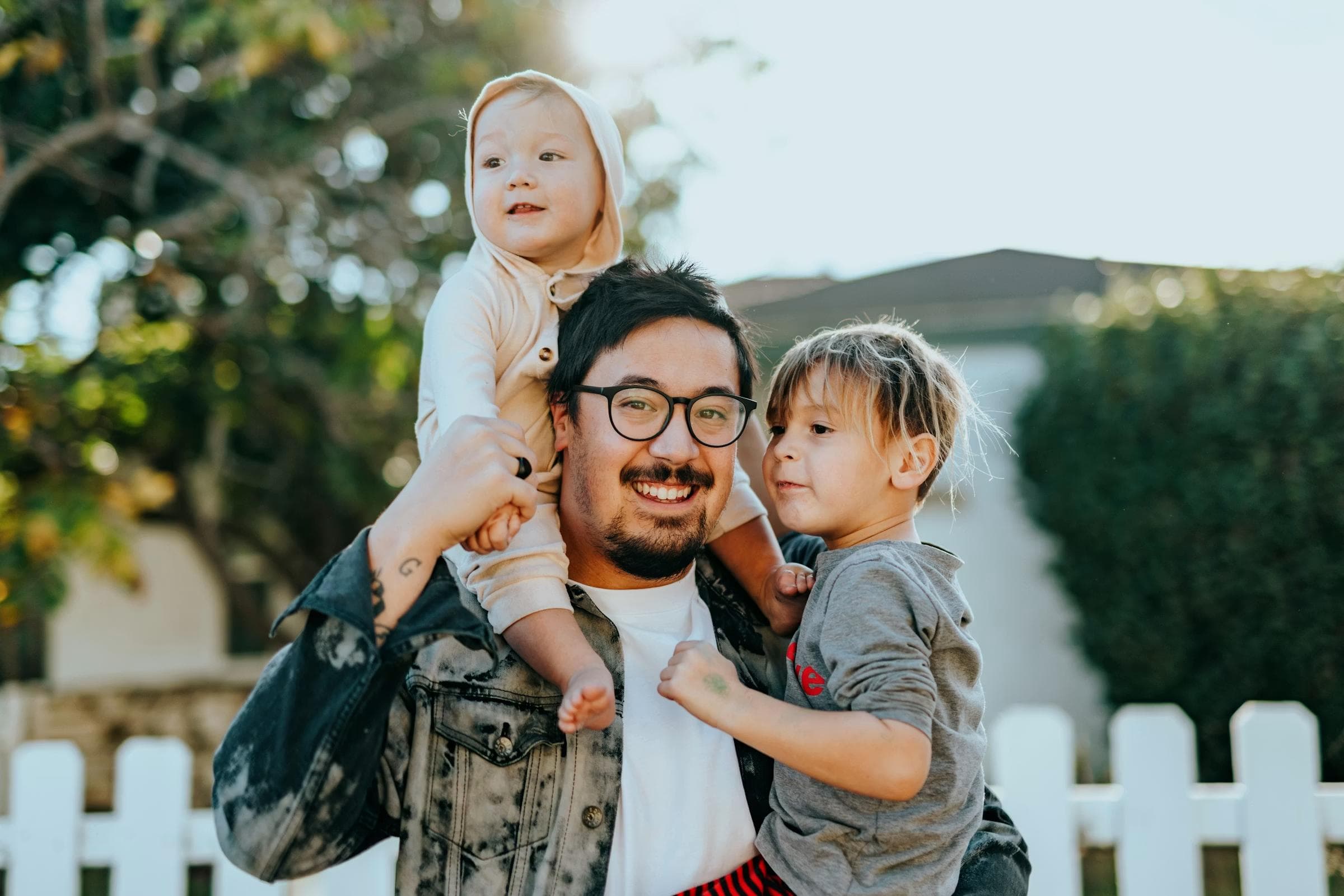 A parent holding two young children outdoors
